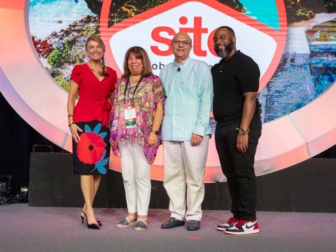 A group stands and smiles at the camera