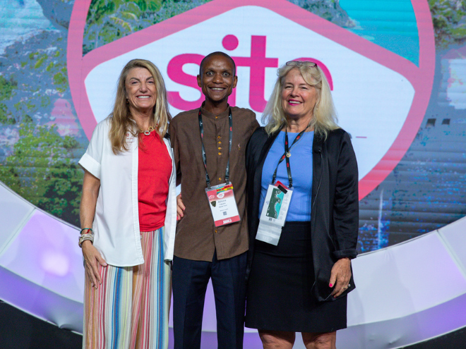 A group stands and smiles at the camera