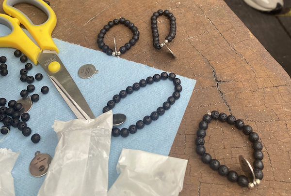 beaded bracelets sit on a wooden tree slab